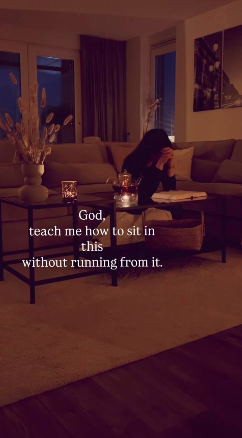 A woman praying by candlelight with her Bible &mdash; God, teach me how to sit in this without running from it.