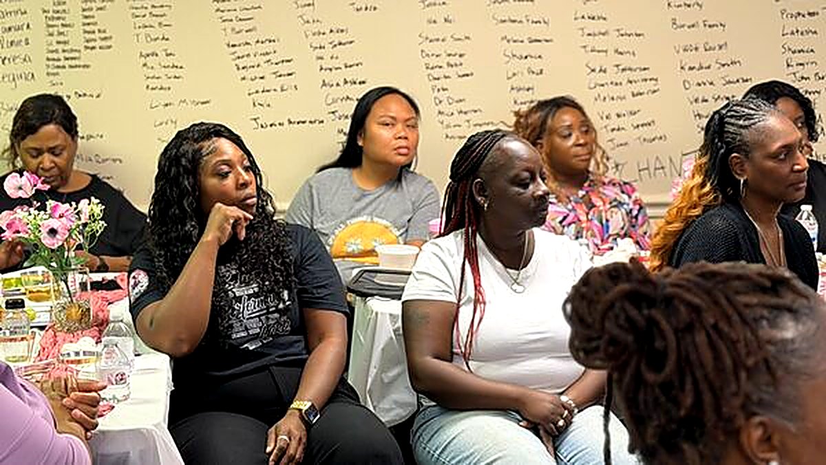 The room of women gathered beneath the wall of prayer names