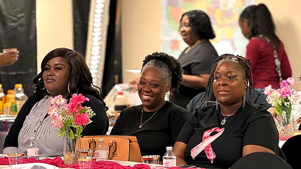 Sisters laughing together at a table decorated with pink flowers